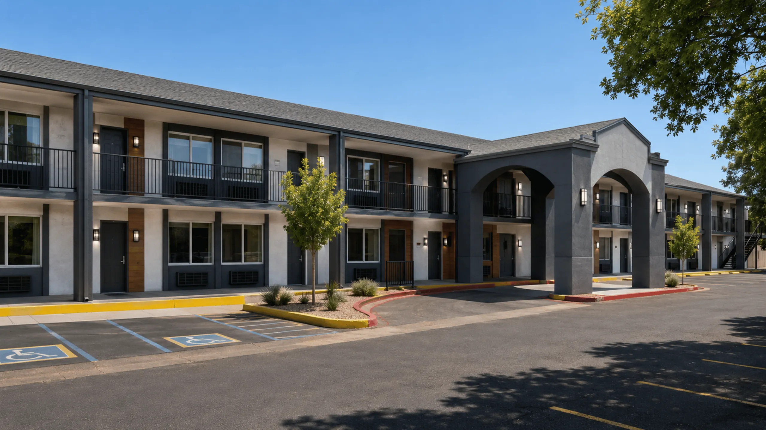 Charming two-story apartment complex with modern design, spacious balconies, and lush greenery under a clear blue sky.