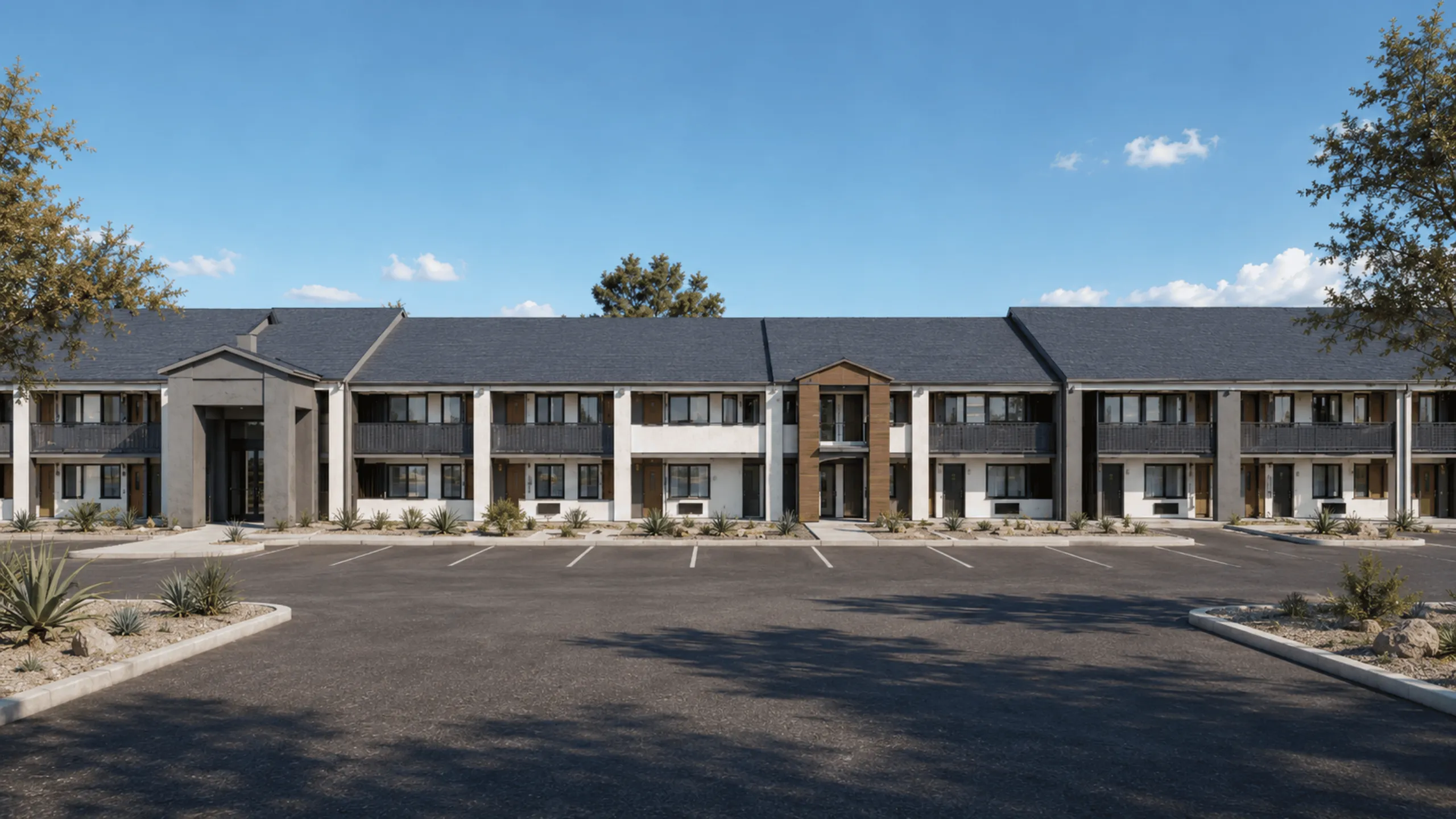 Contemporary apartment complex with modern fa&ccedil;ade, ample parking, and lush landscaping under a clear blue sky.