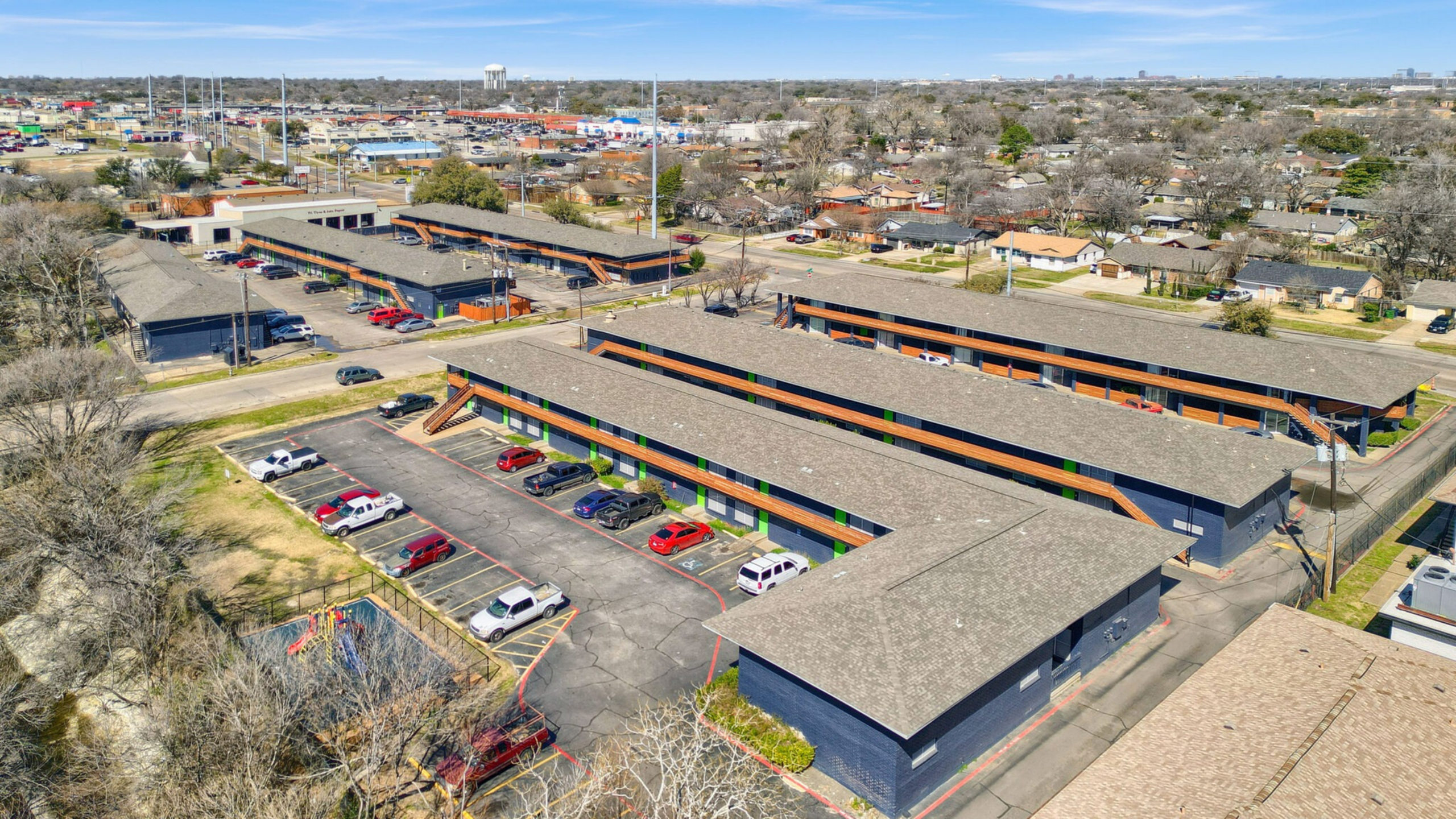 Aerial view of a modern apartment complex with ample parking and scenic surroundings, offering easy access to nearby urban amenities.