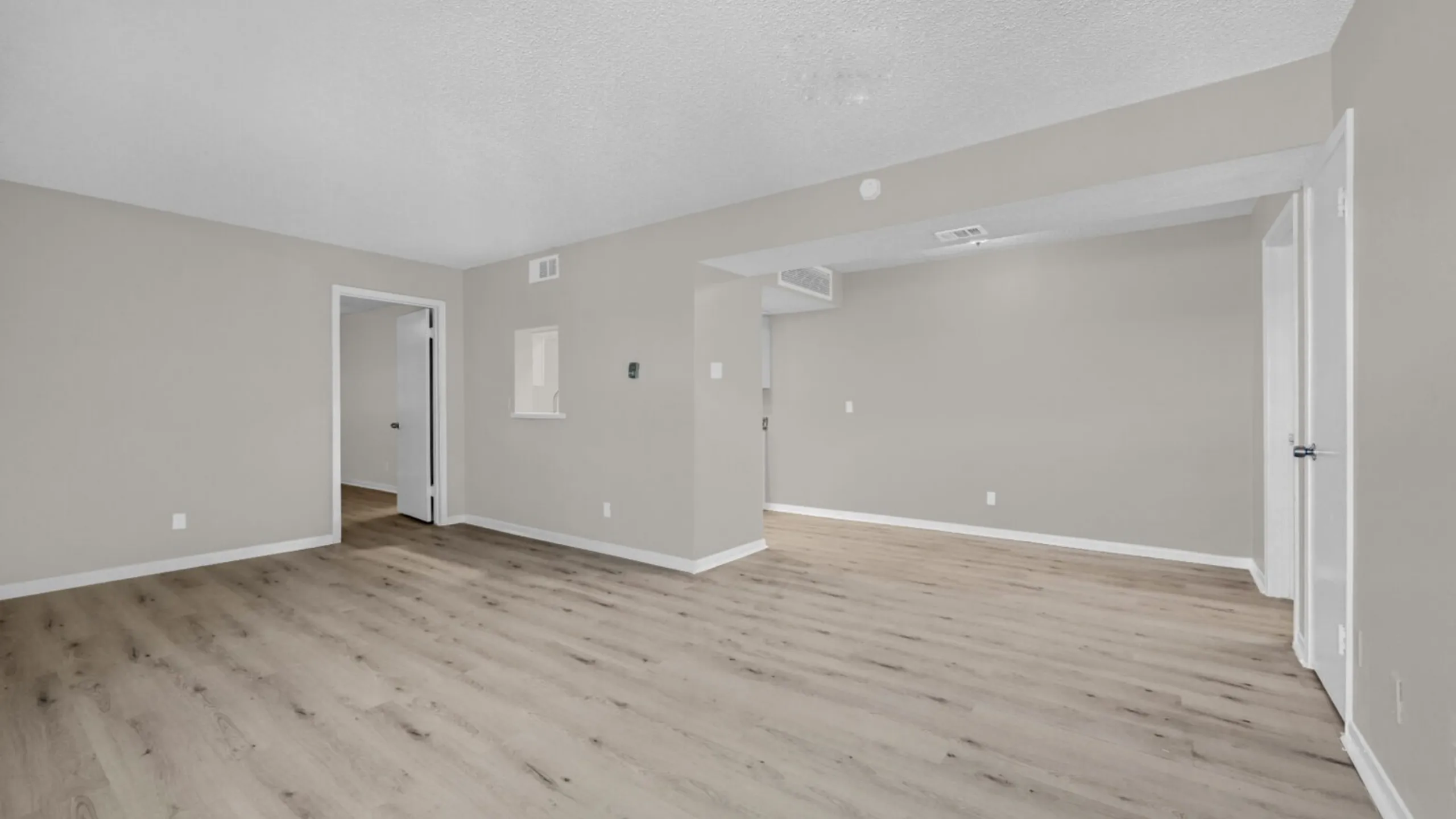 Inviting open-concept living space with elegant wooden flooring and neutral wall tones, perfect for customization.