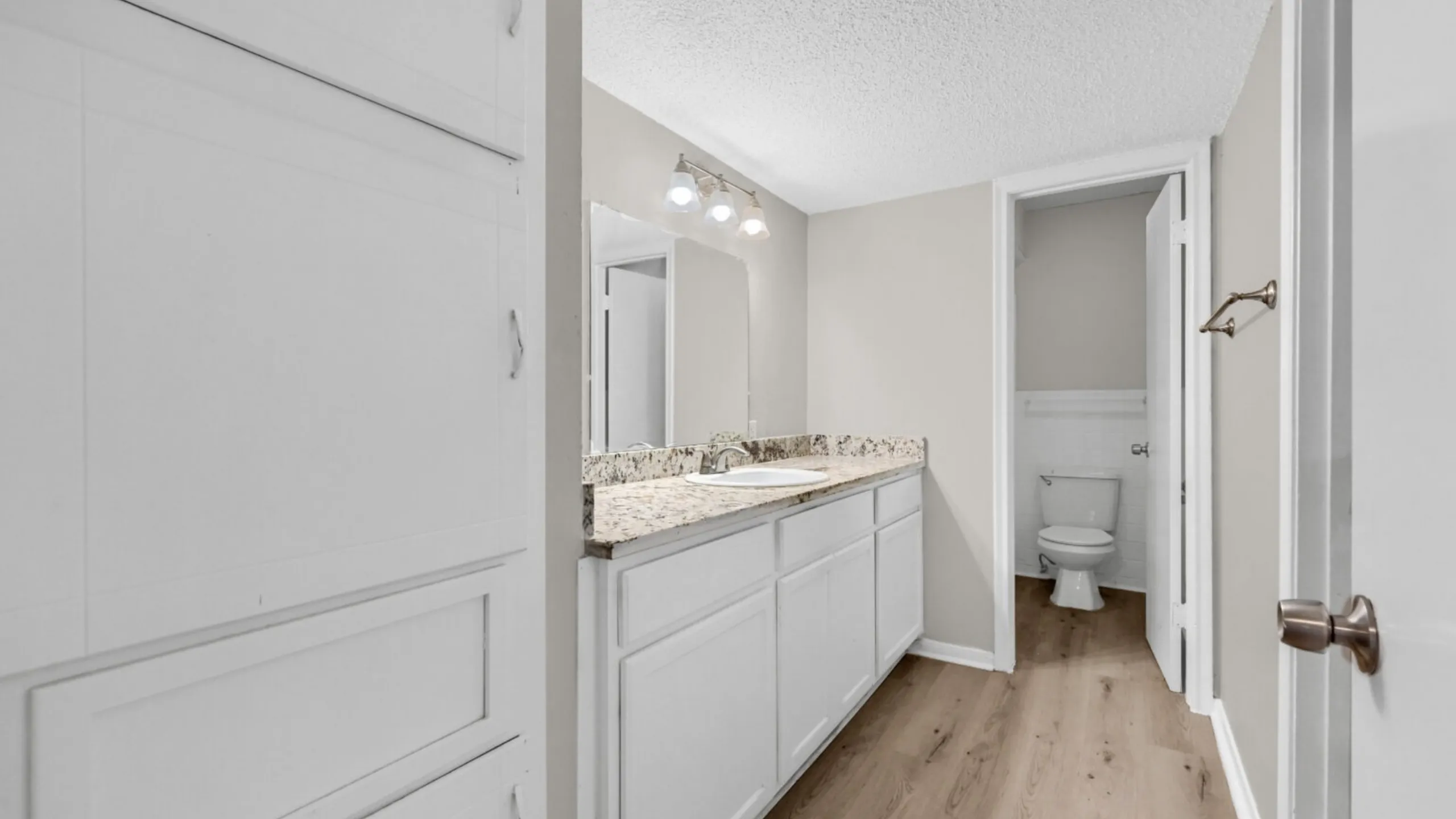 Bright, modern bathroom featuring elegant granite countertops and ample cabinetry, promising a stylish and functional space.