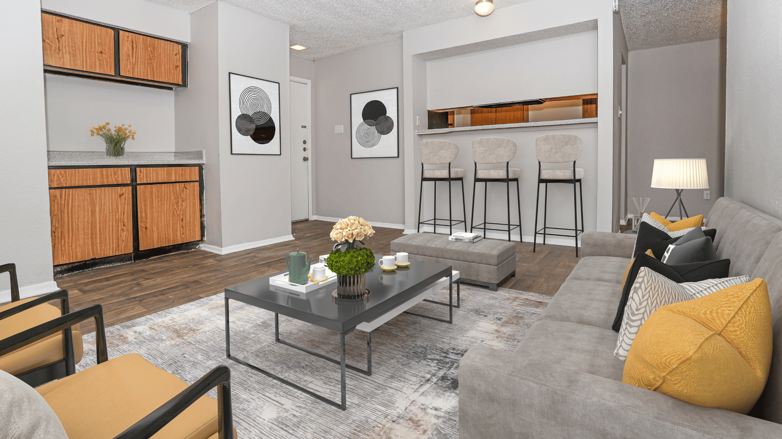 Modern living room with cozy gray sofas, vibrant yellow cushions, and a sleek coffee table. Open kitchen area with stylish bar stools and elegant wooden cabinets, perfect for entertaining.