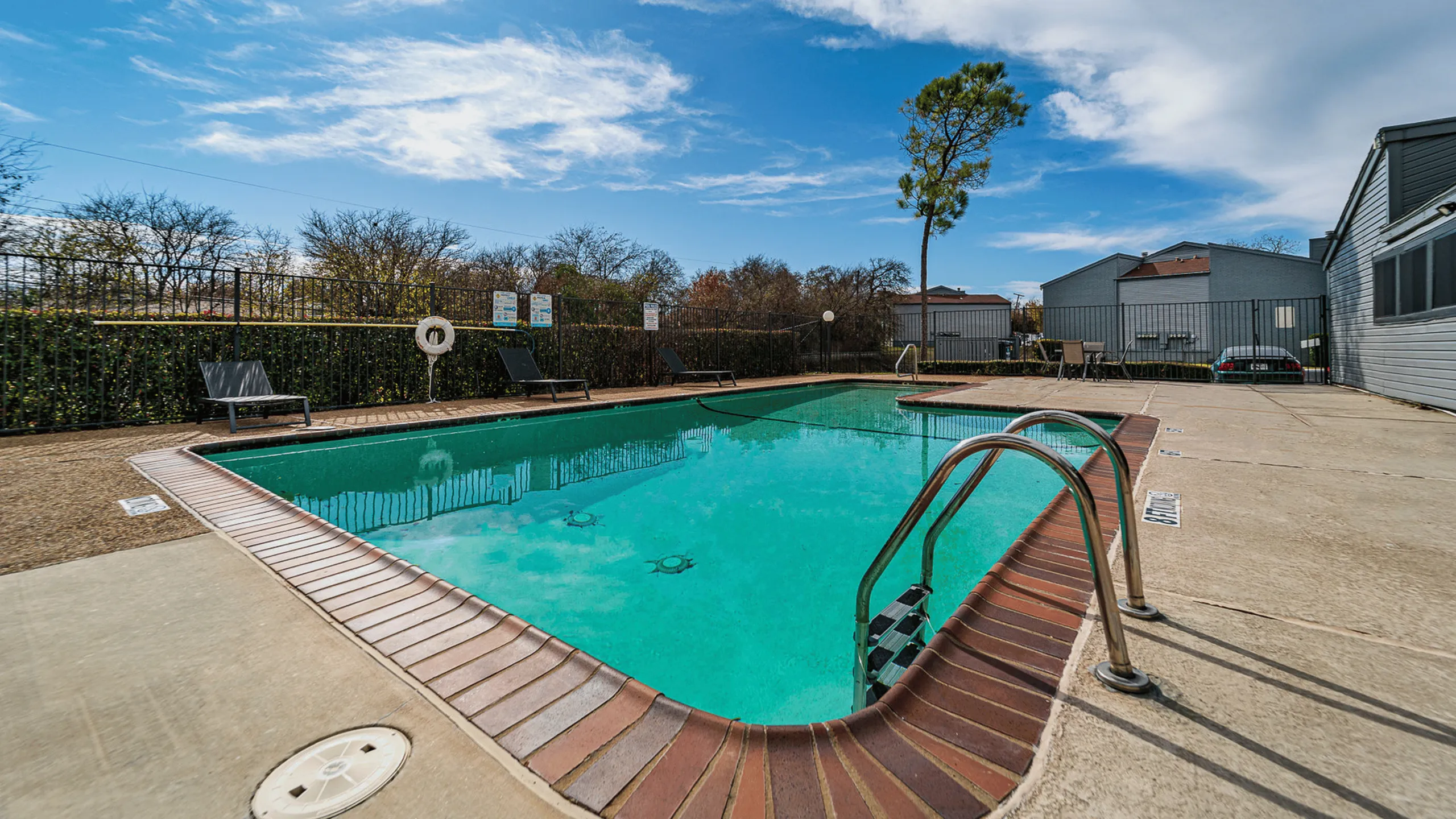 Inviting outdoor pool area with clear blue water, modern sun loungers, and a serene natural backdrop.