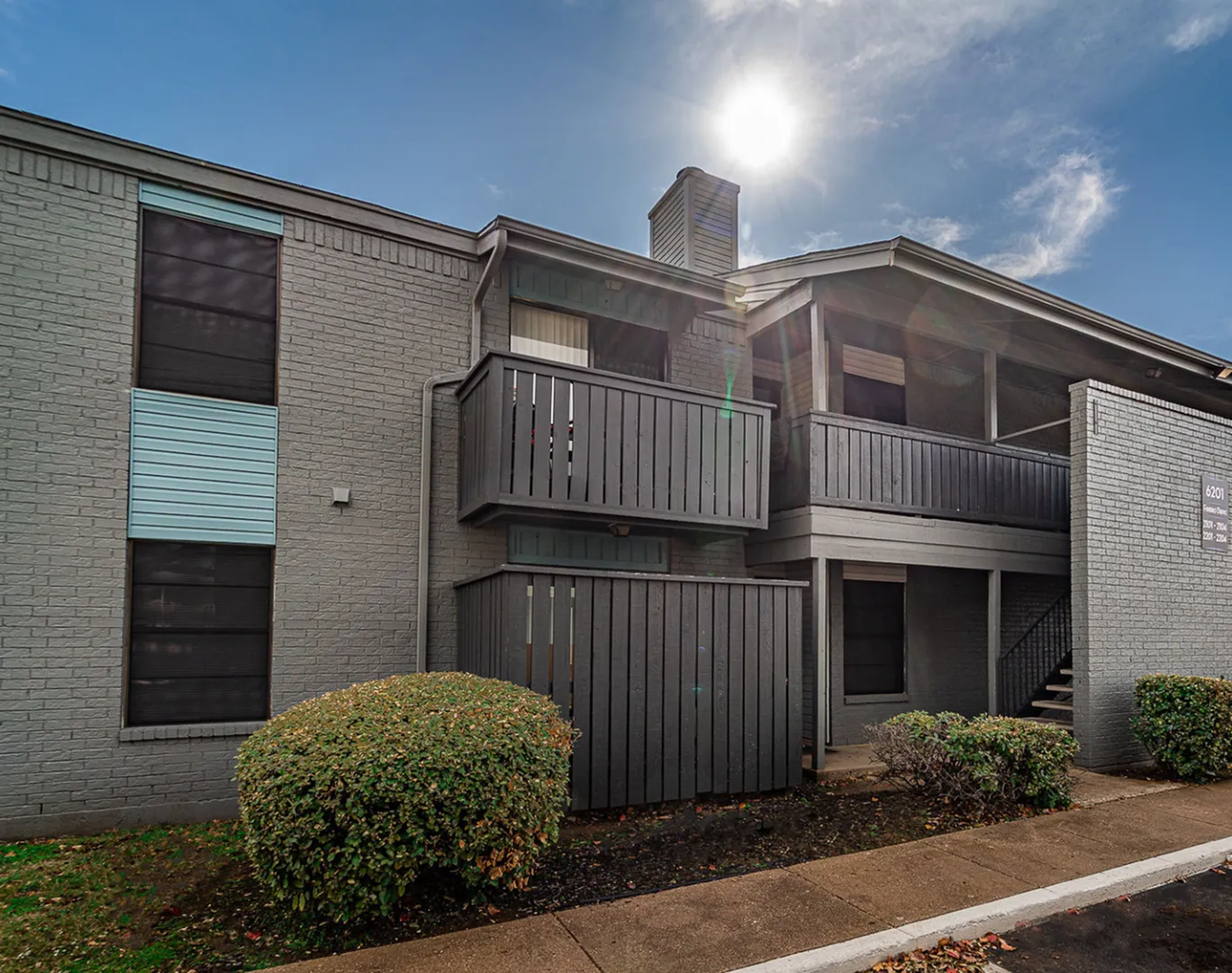 Modern apartment building with stylish gray exterior, sunny balconies, and well-maintained landscaping.