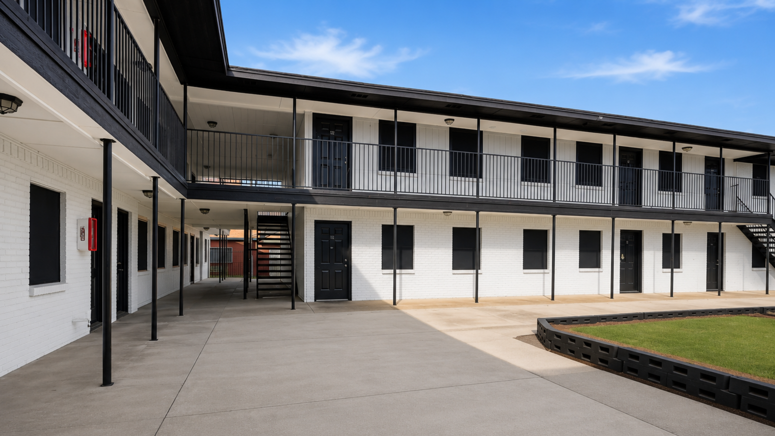 Modern apartment complex with sleek black railing, spacious walkways, and a charming courtyard.