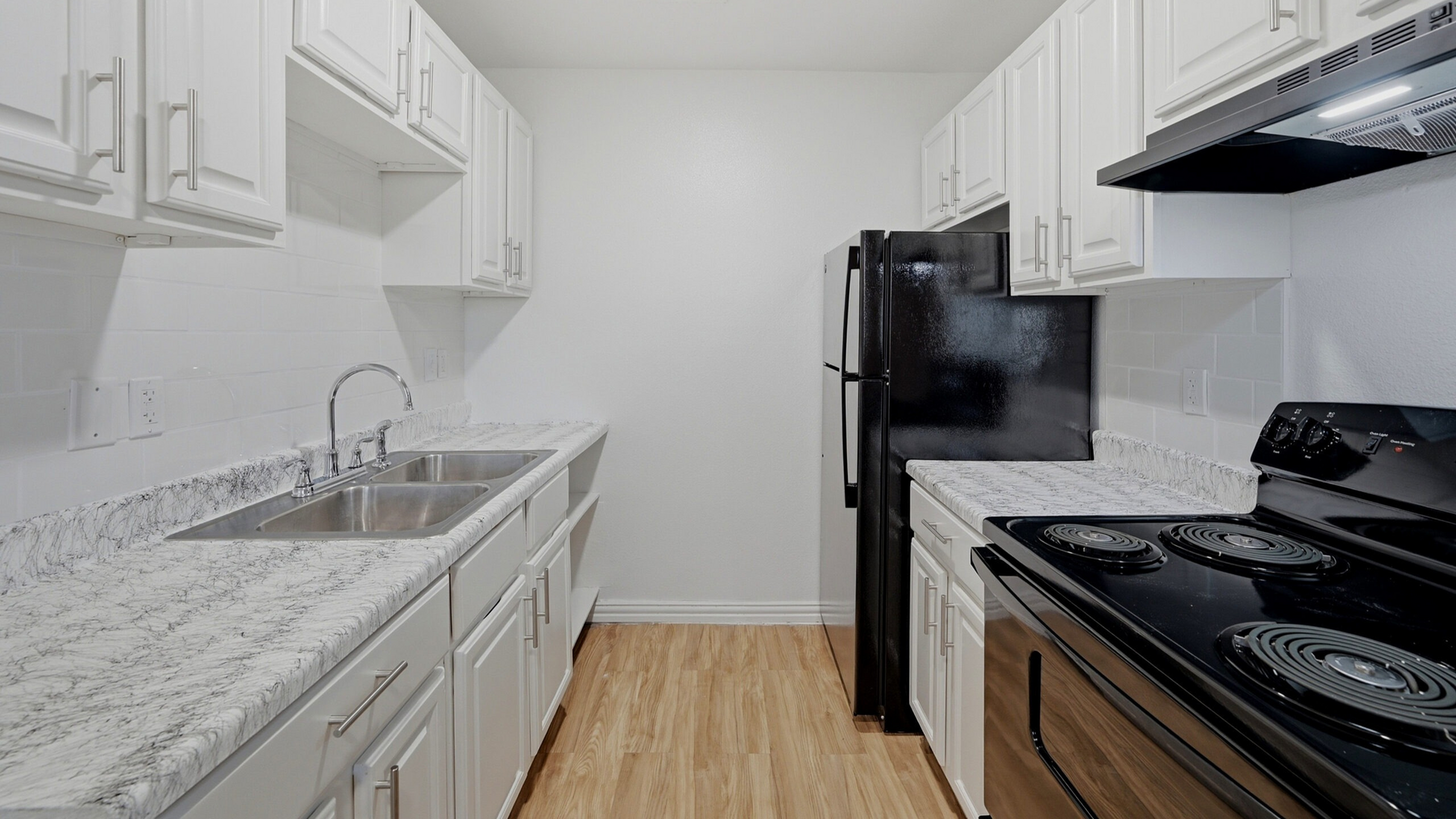 Contemporary kitchen with sleek white cabinetry, elegant marble countertops, and modern appliances in a cozy layout.