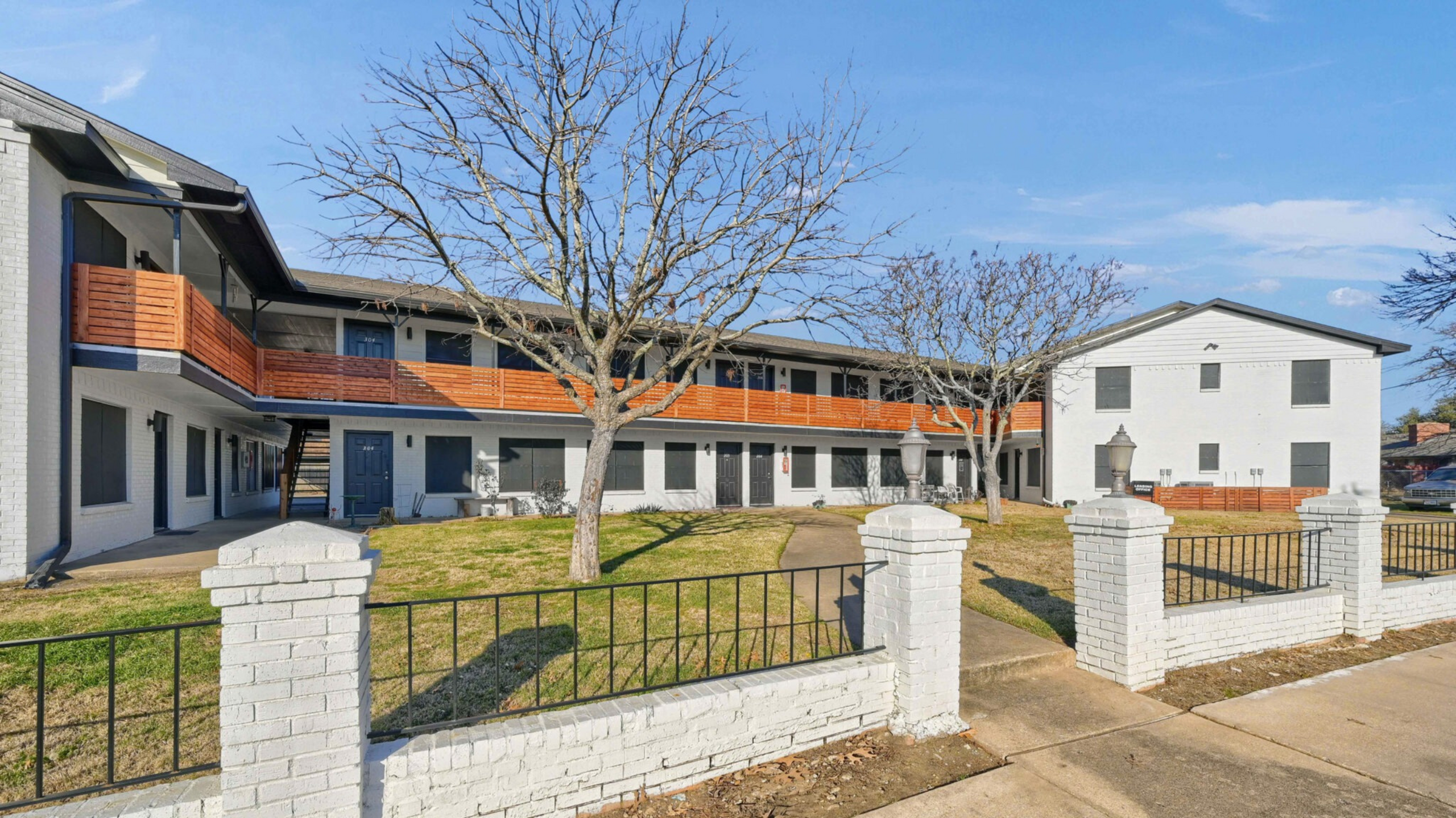 Charming apartment complex with modern wood accents, manicured lawns, and inviting outdoor spaces.