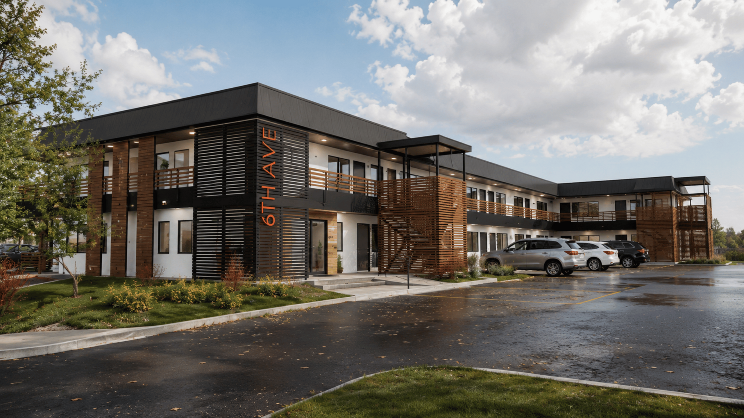 Modern two-story apartment complex with stylish wooden accents and ample parking at 6th Avenue.
