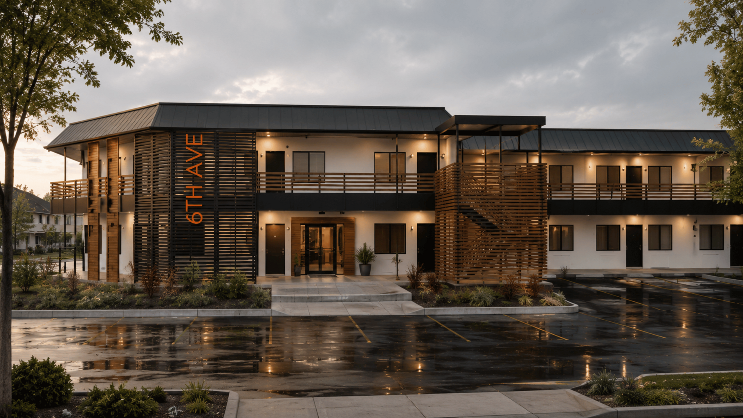 Modern apartment complex with sleek design, featuring wood finishes, warm lighting, and inviting landscaped entrance at 6th Avenue.