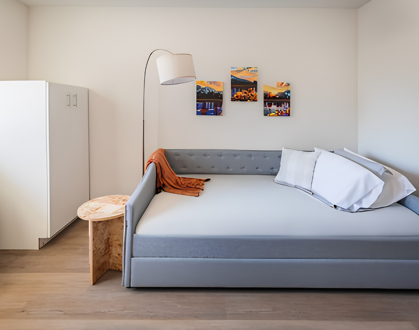 Modern bedroom with a sleek gray daybed, cozy orange throw, and stylish wall art, perfect for a serene retreat.