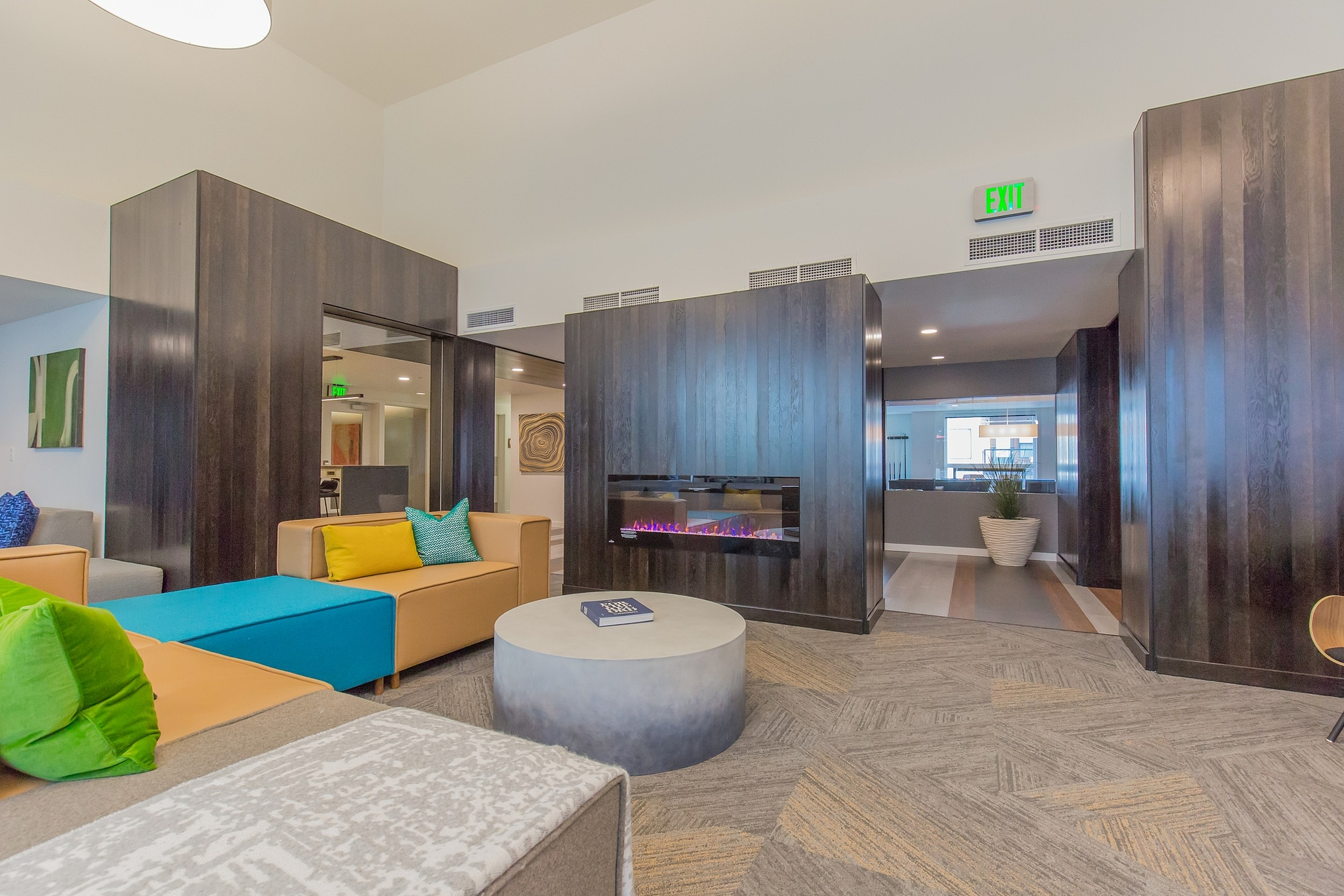 Modern lounge with vibrant seating, a stylish fireplace, and elegant decor, offering a cozy and inviting atmosphere.