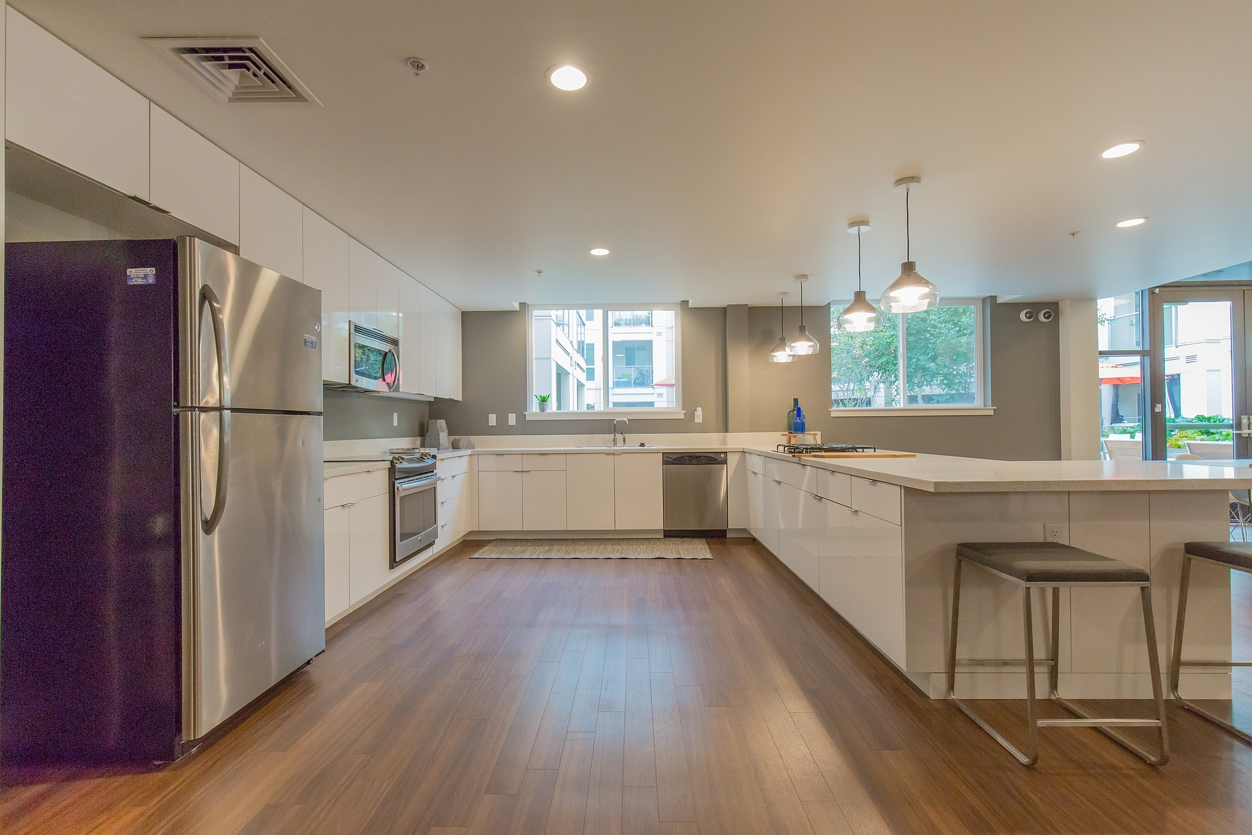 Contemporary kitchen with sleek white cabinetry, stainless steel appliances, and elegant pendant lighting, showcasing a spacious open layout.