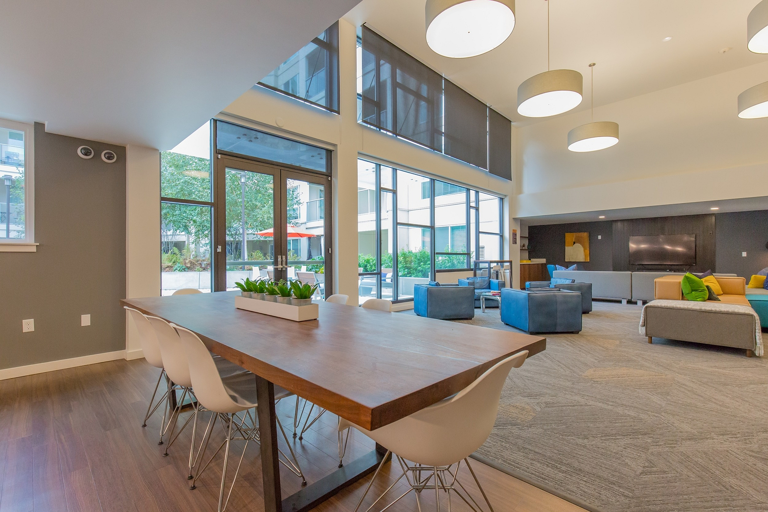 Inviting and modern communal living space with high ceilings, abundant natural light, chic décor, and stylish seating, perfect for social gatherings.