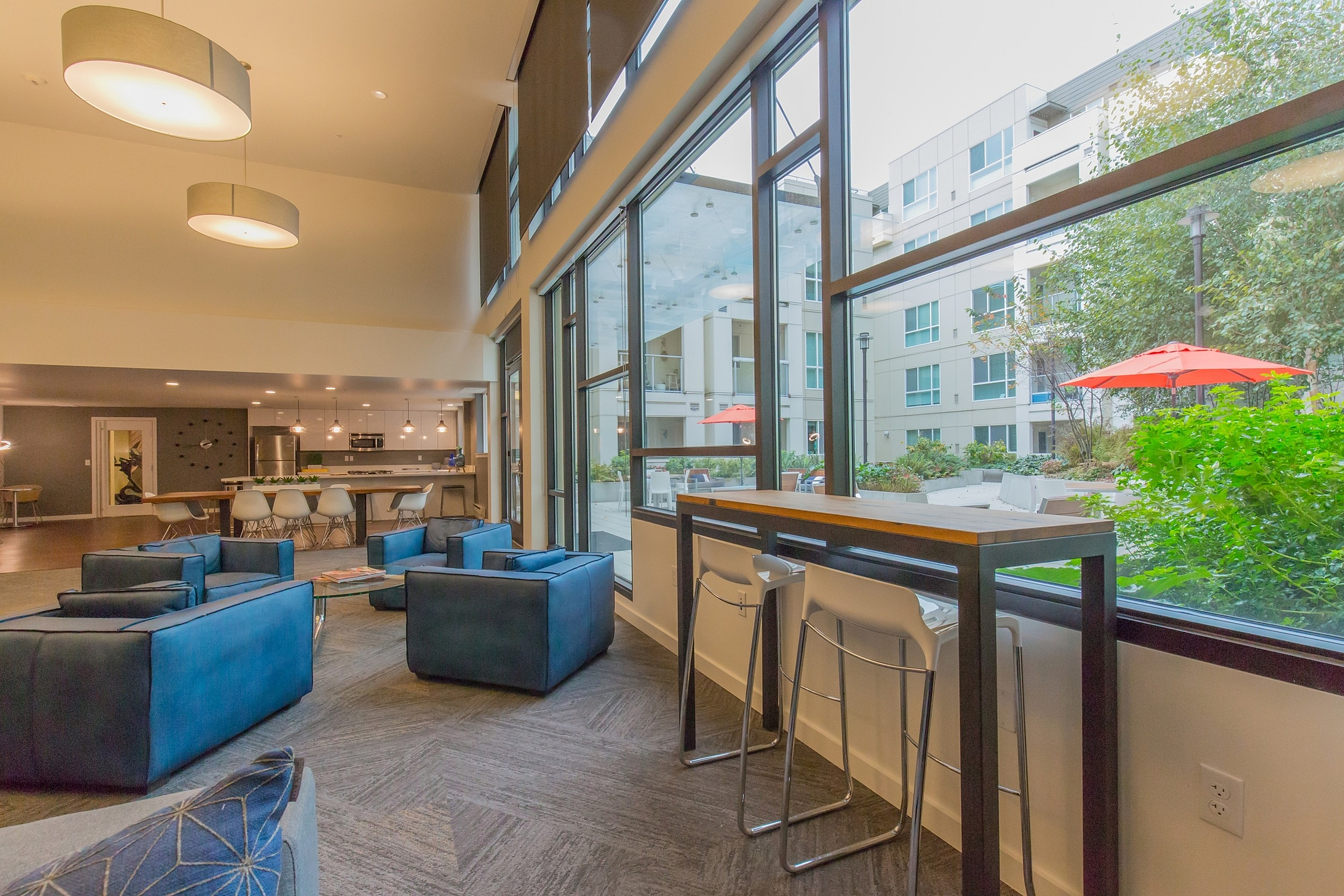 Bright and modern lounge area with large windows, stylish seating, and a view of a vibrant courtyard.