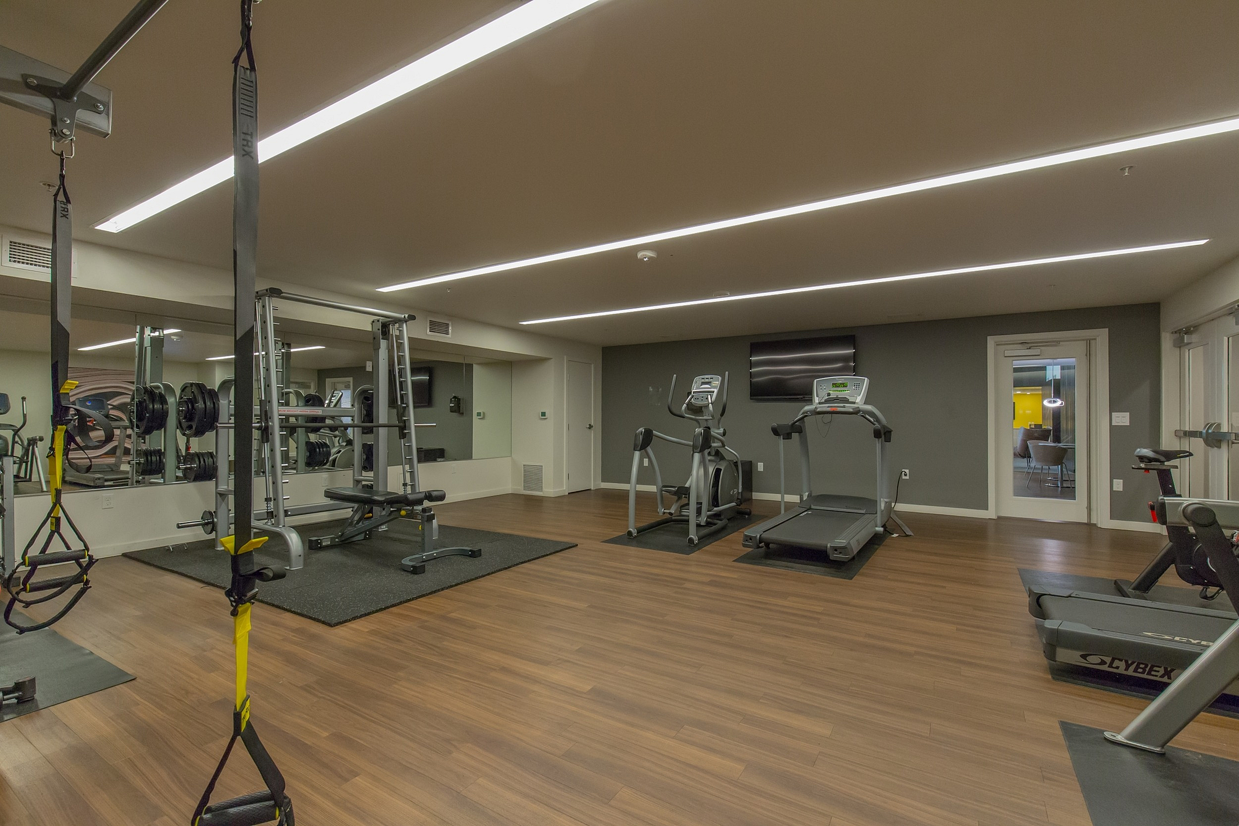 Modern fitness center featuring state-of-the-art exercise equipment, including treadmills and weight machines, on sleek wood flooring.