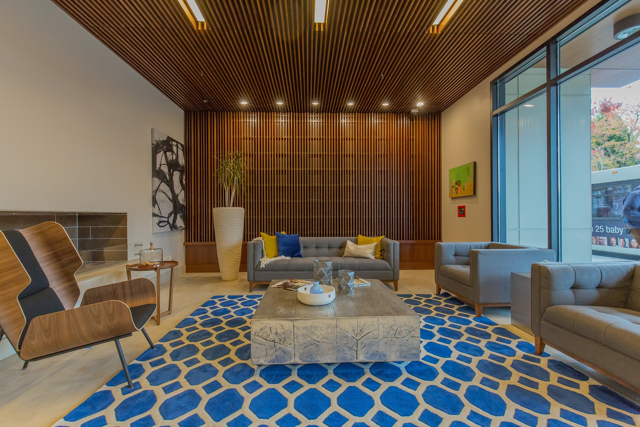 Contemporary lounge area with stylish wooden accents, plush seating, and a vibrant blue geometric rug, perfect for relaxation.