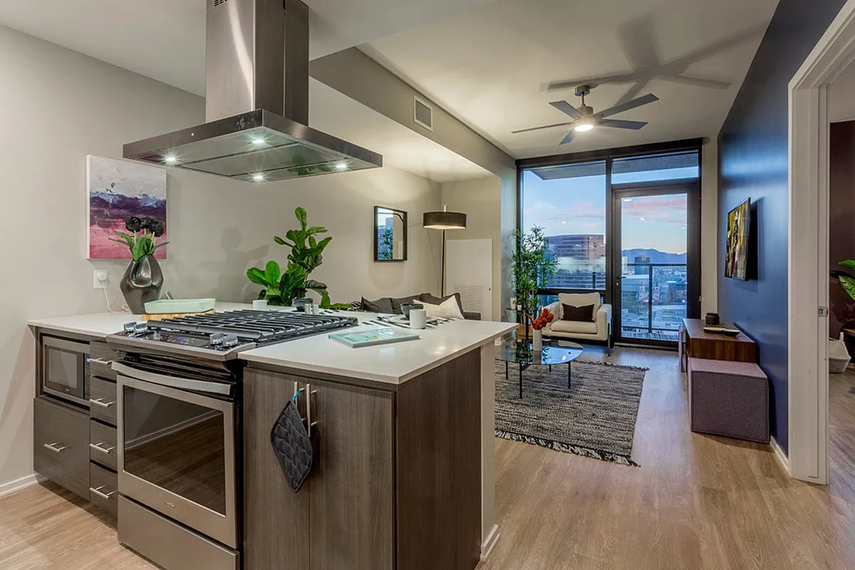 Modern open-concept apartment with sleek kitchen island, inviting living area, and floor-to-ceiling windows with panoramic city views.