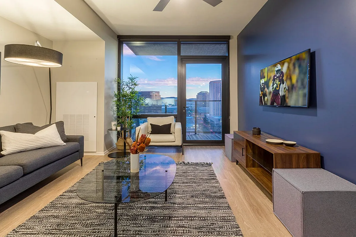 Modern living room with chic decor, featuring a cozy seating area, stylish entertainment setup, and a stunning city view through expansive windows.
