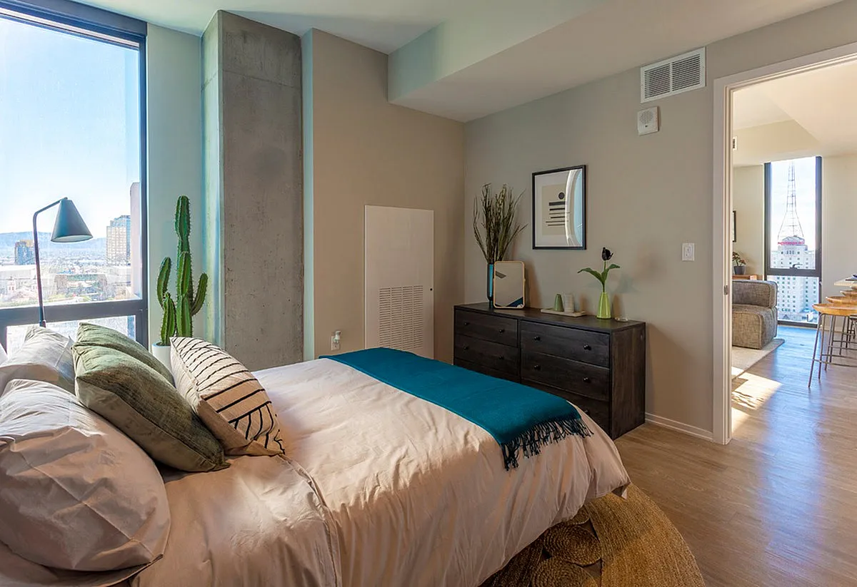 Modern bedroom with large window view, cozy decor, and access to a bright living area.