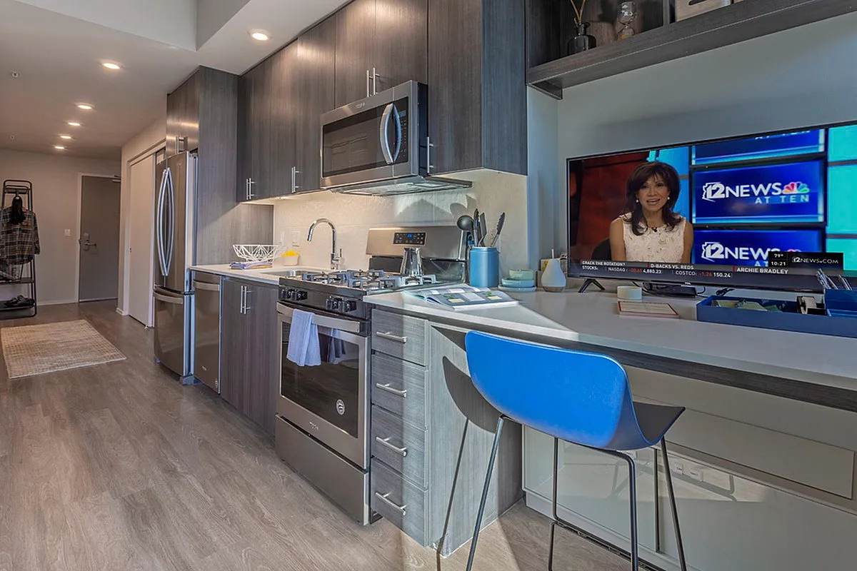 Modern kitchen with sleek cabinetry, stainless steel appliances, and a cozy breakfast bar with a vibrant blue stool. Ideal for entertaining and everyday living.