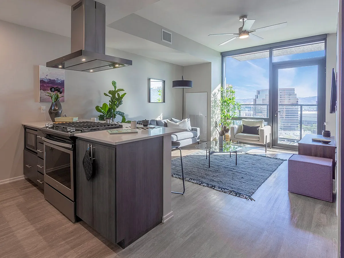 Contemporary urban apartment with a stylish kitchen island, cozy living area, and floor-to-ceiling windows offering stunning city views.