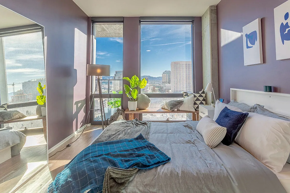 Elegant bedroom with modern furnishings, large windows offering stunning city views, and abundant natural light.