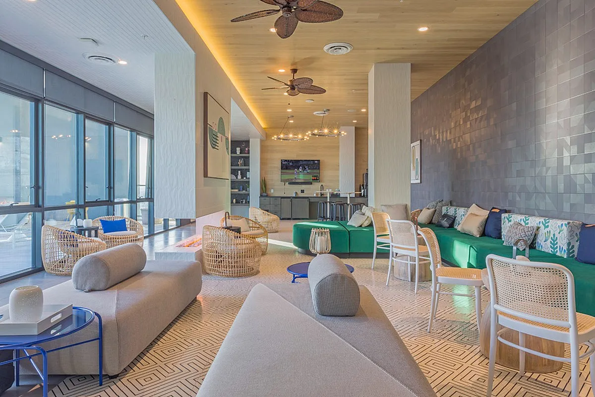 Contemporary lounge area with stylish seating, ceiling fans, and large windows offering natural light and views.