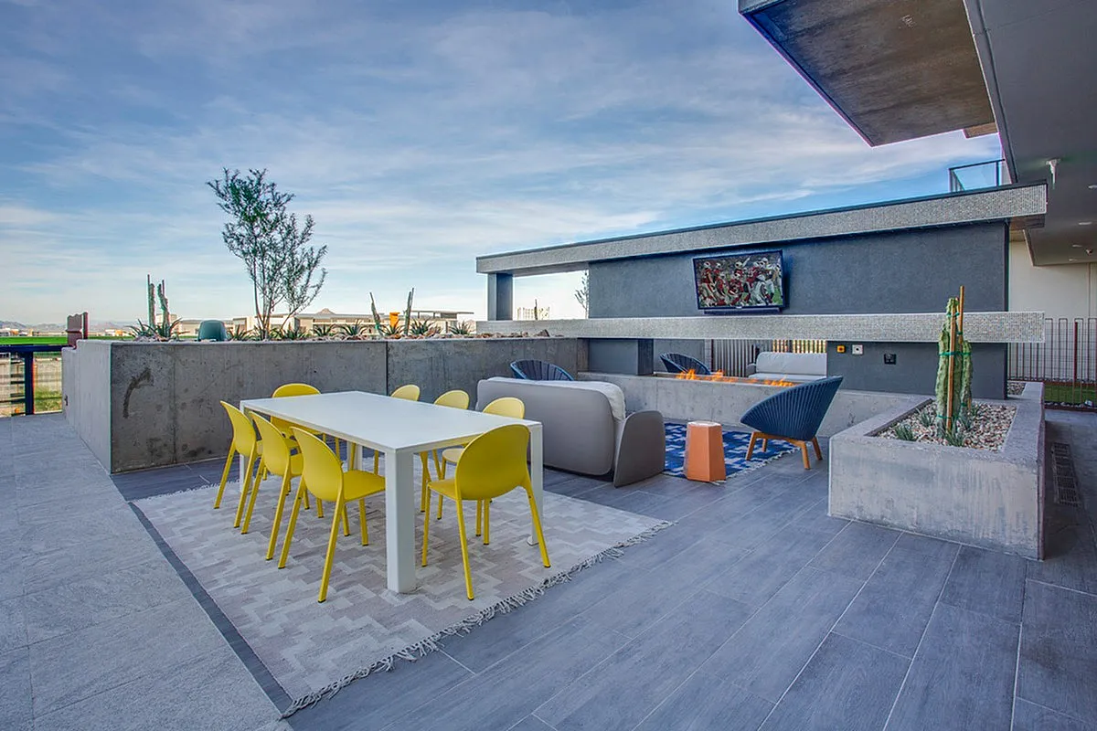 Modern rooftop terrace with vibrant yellow dining chairs, sleek white table, and cozy lounge area with outdoor TV and fire pit.