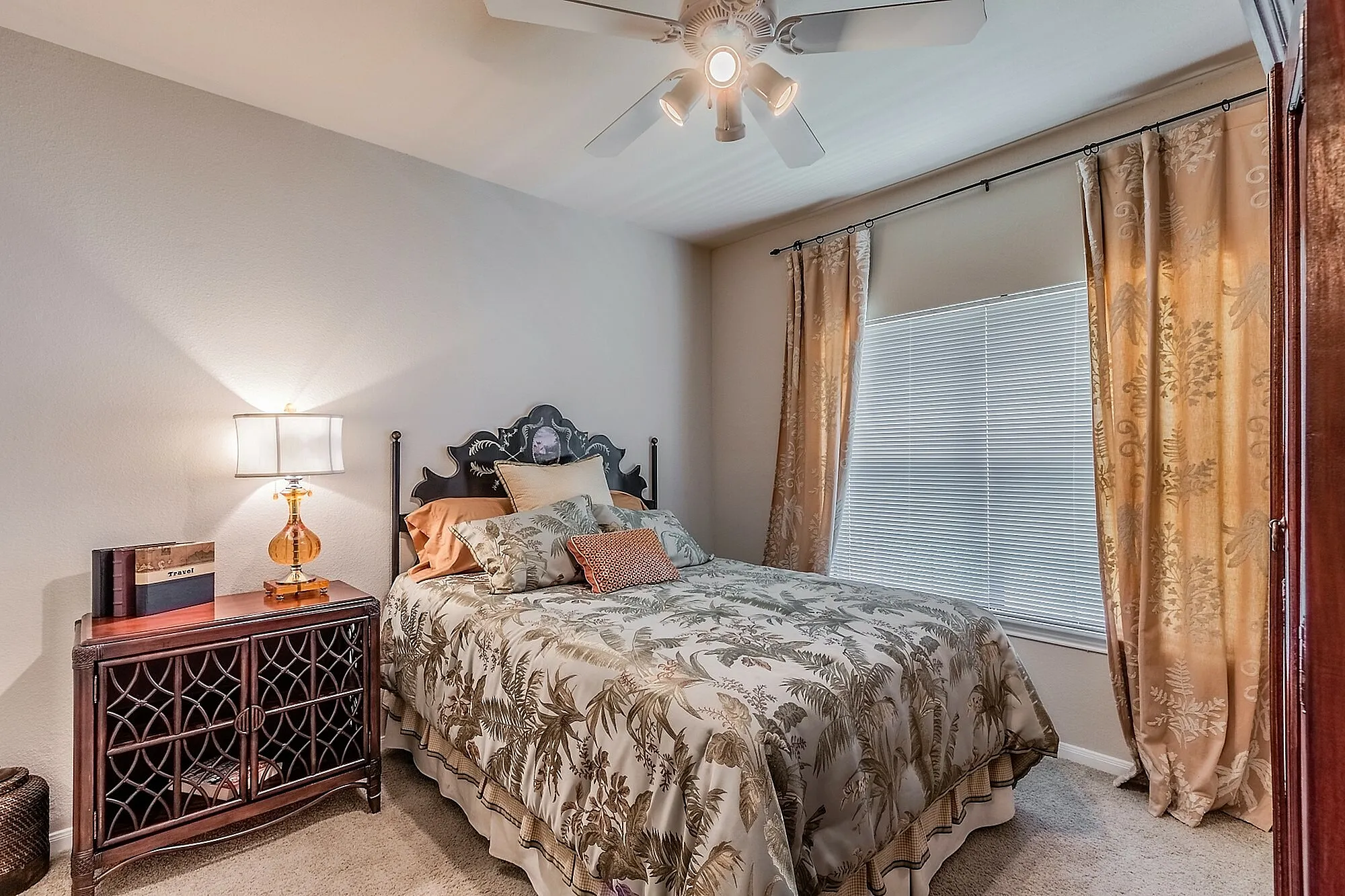 Cozy bedroom with elegant decor, featuring a stylish bedspread, ornate headboard, and warm lighting beside the window.