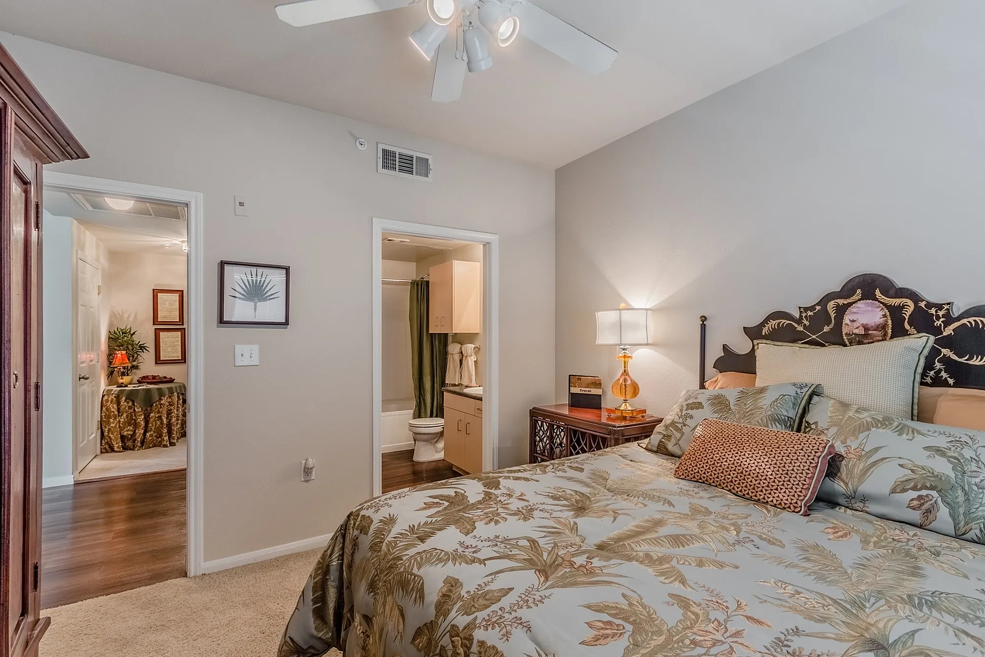 Cozy bedroom with elegant bedding and warm lighting, adjoining a modern en-suite bathroom and charming hallway.