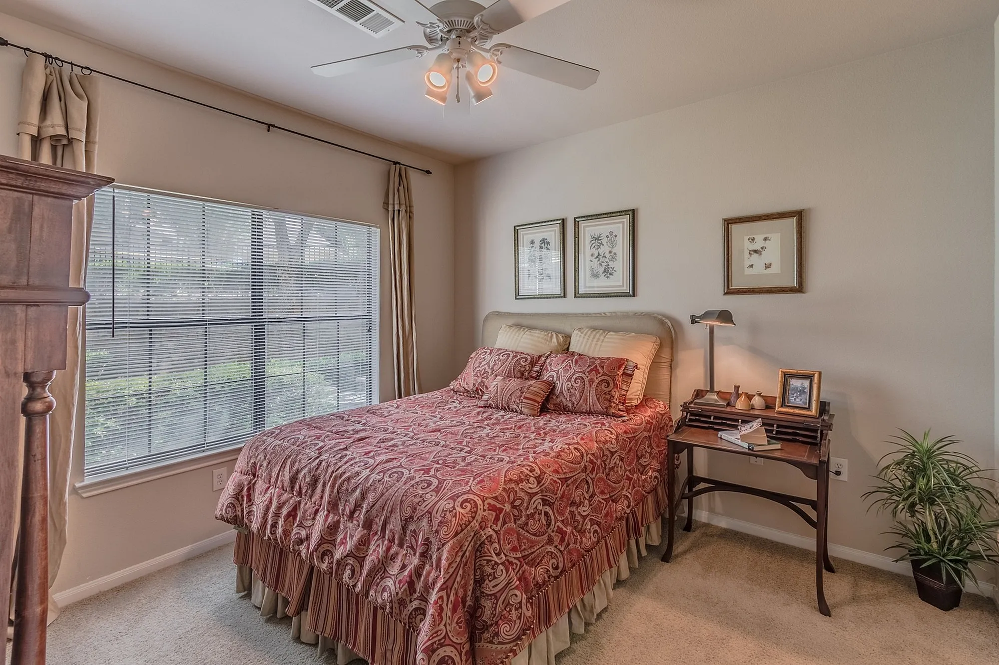 Inviting bedroom with elegant decor, featuring a cozy bed with a vibrant patterned duvet, large window for natural light, and stylish artwork.