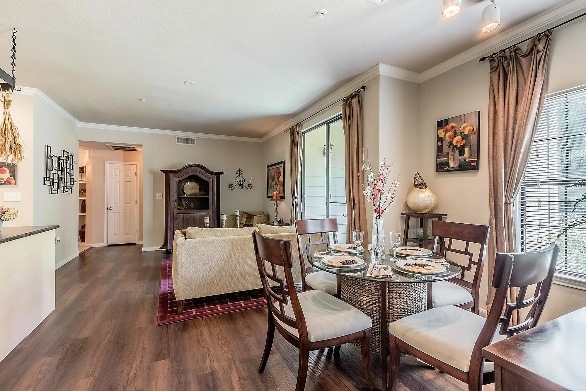 Elegant living and dining area with abundant natural light, featuring stylish furniture and a cozy dining setup perfect for entertaining.