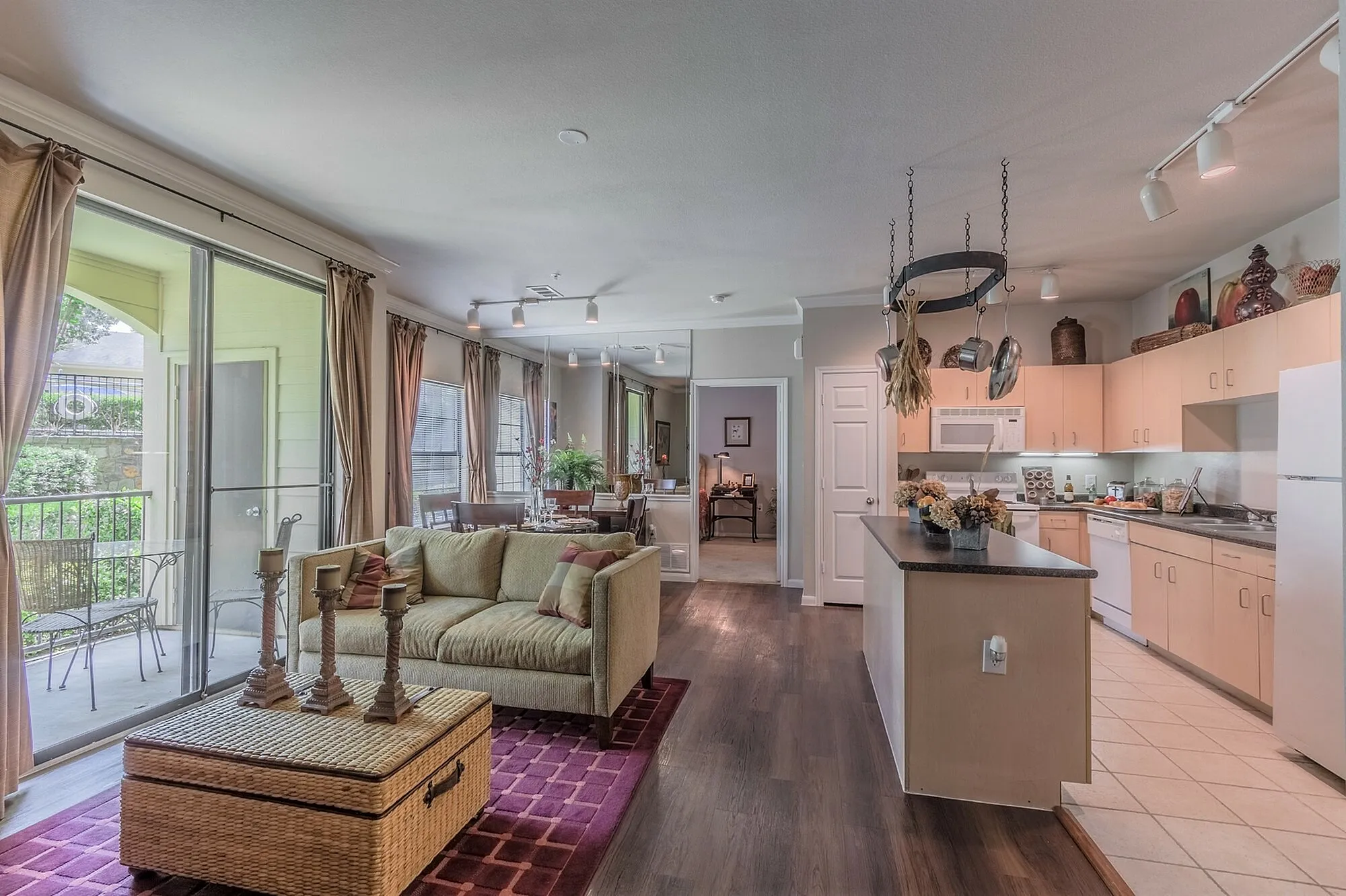 Inviting open-concept living room and kitchen with bright natural light, elegant decor, and a cozy balcony view.