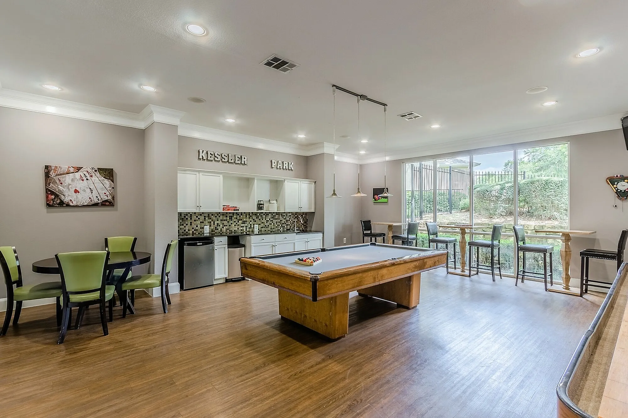 Chic recreation room featuring a stylish pool table, elegant seating, and a well-lit kitchenette, perfect for entertaining guests.