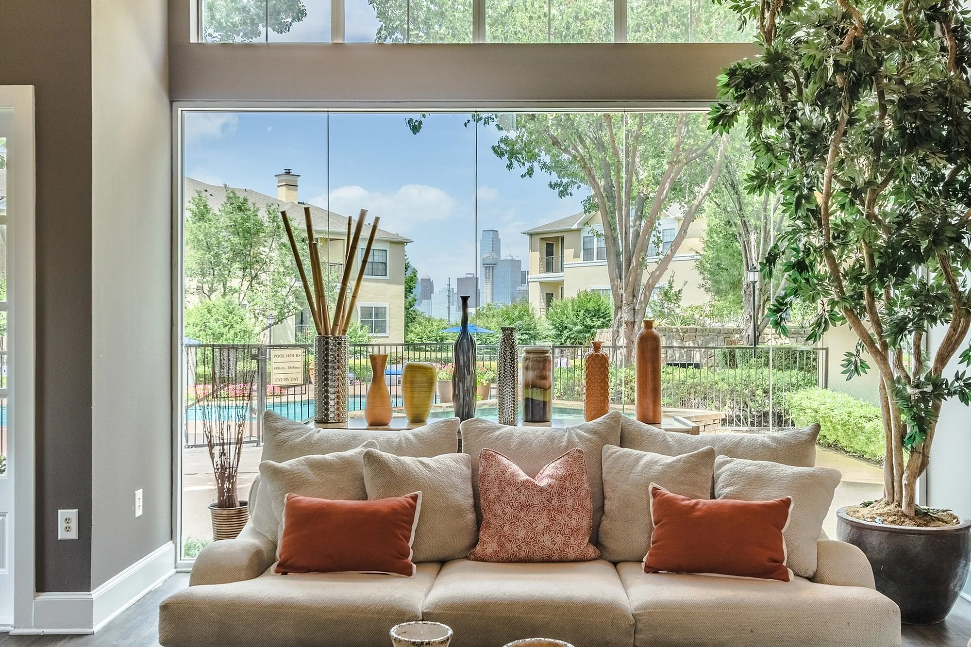 Luxurious living room with plush sofa, elegant decor, and expansive windows offering a stunning view of the garden and city skyline.