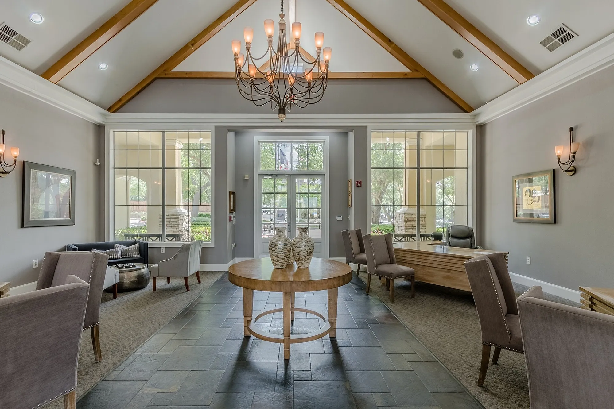 Elegant community lounge with vaulted ceilings, modern chandelier, and comfortable seating areas, perfect for relaxation and social gatherings.