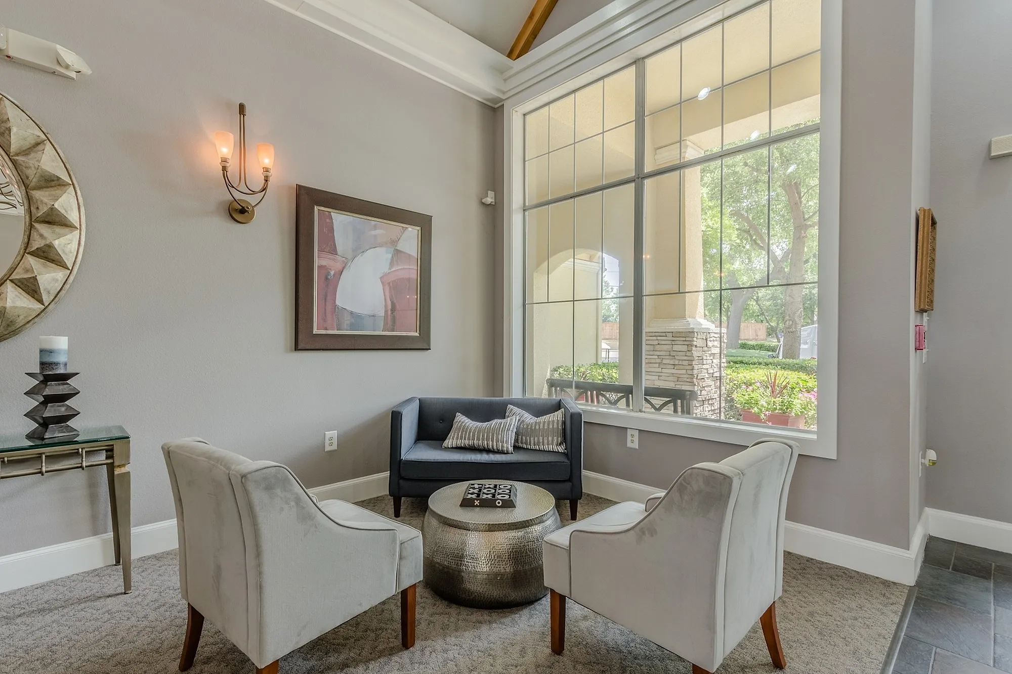 Elegant and cozy apartment lounge featuring plush seating, stylish decor, and large windows with serene garden views.