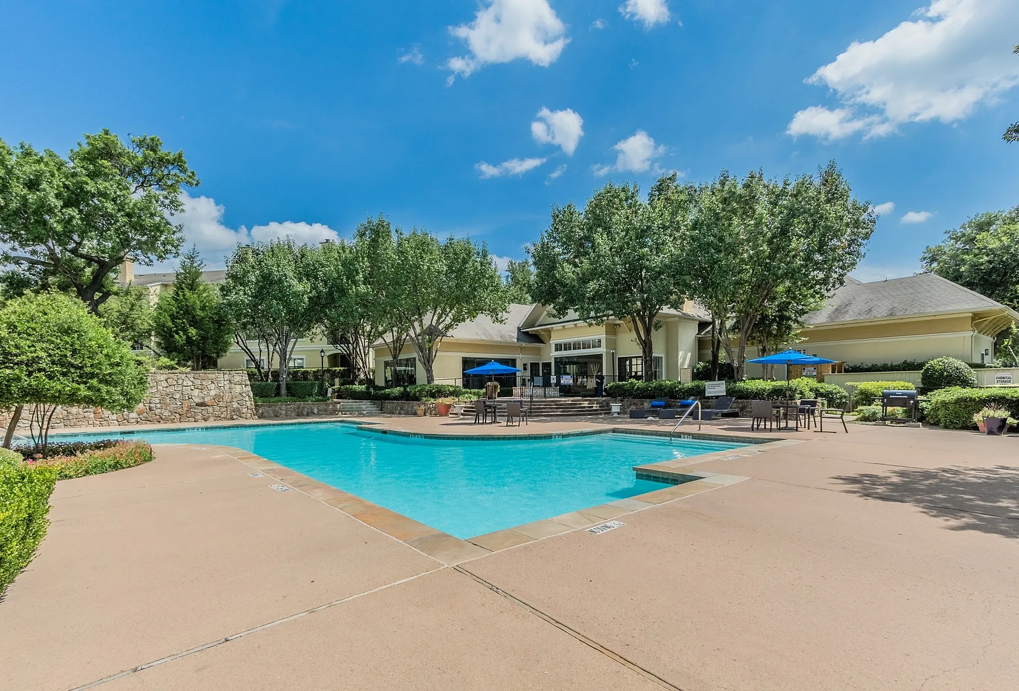 Inviting outdoor pool area surrounded by lush greenery and elegant patio seating, perfect for relaxation and leisure.