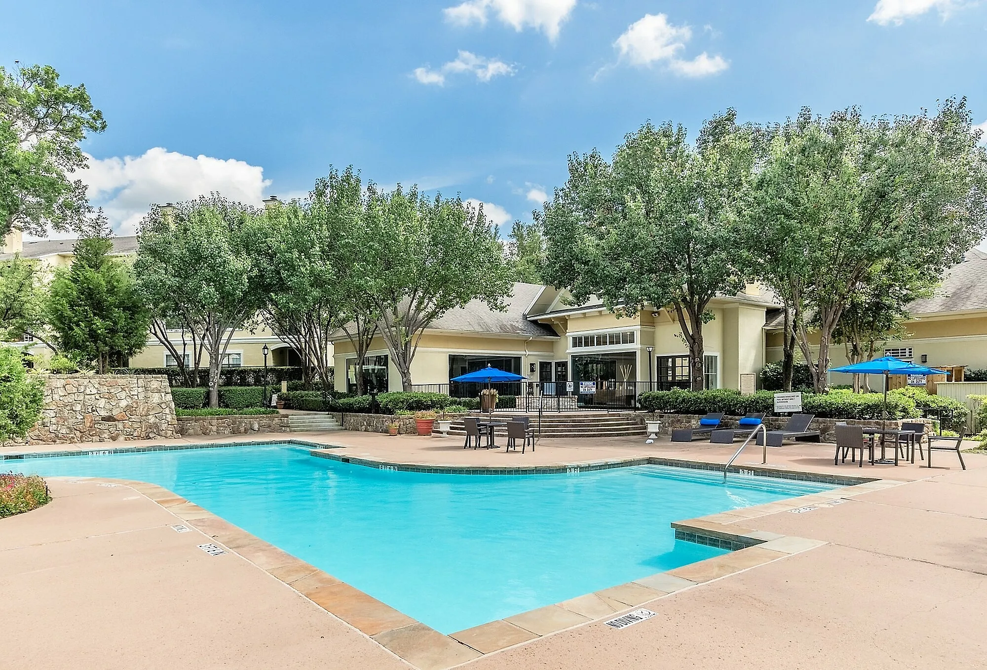 Inviting luxury apartment complex showcasing a sparkling swimming pool, elegant outdoor seating, and lush greenery, perfect for relaxation and leisure.