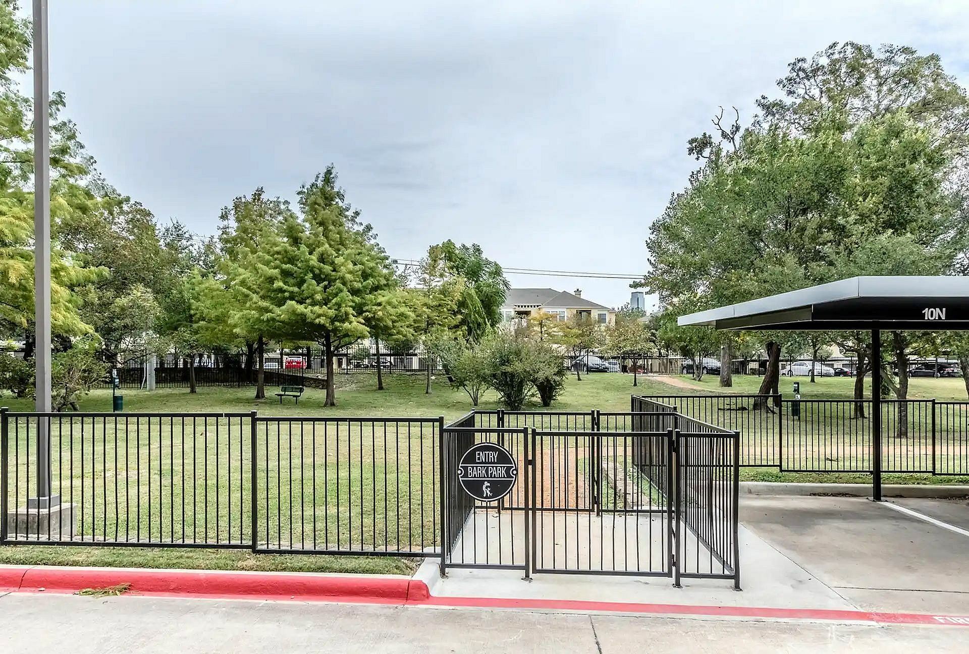 Inviting community park entrance with lush green landscaping and contemporary fencing, perfect for outdoor enjoyment.