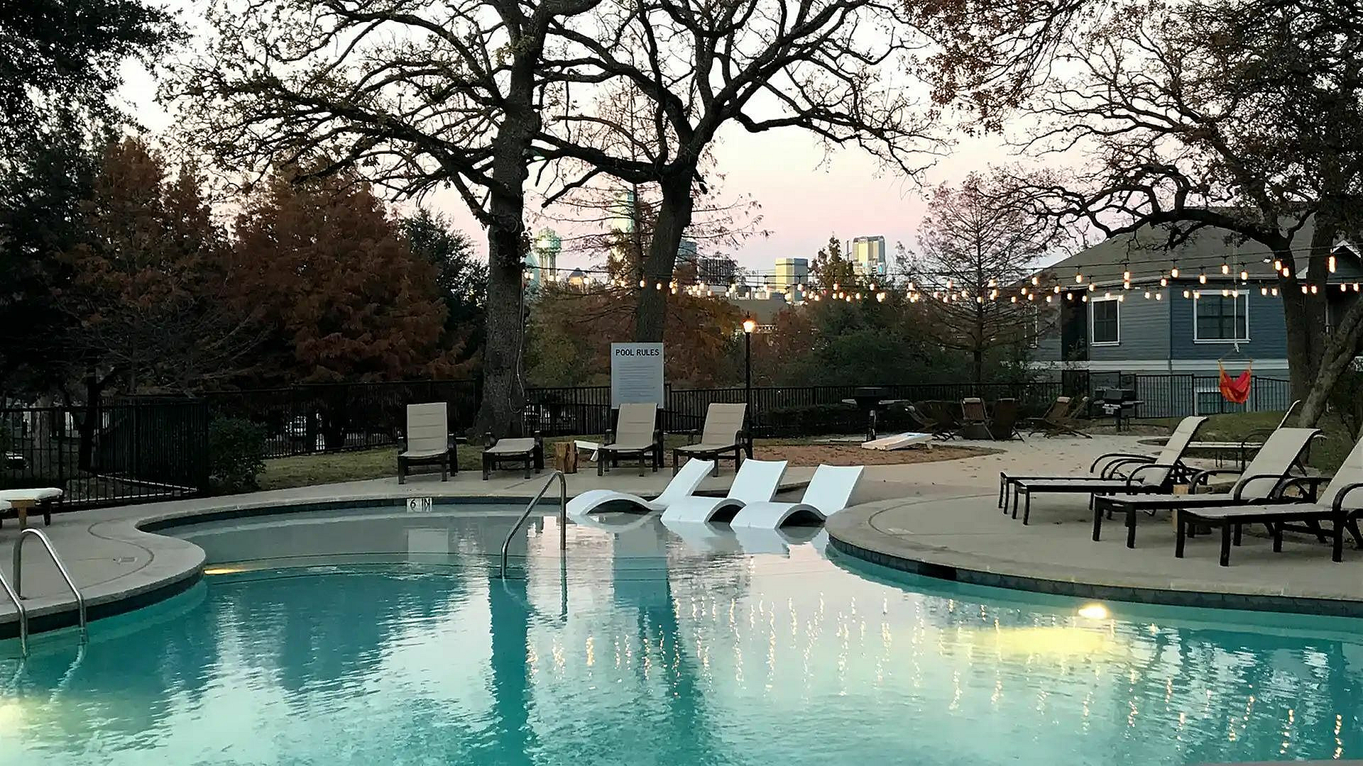 Tranquil poolside scene with elegant loungers and twinkling string lights, perfect for relaxation in a serene outdoor setting.
