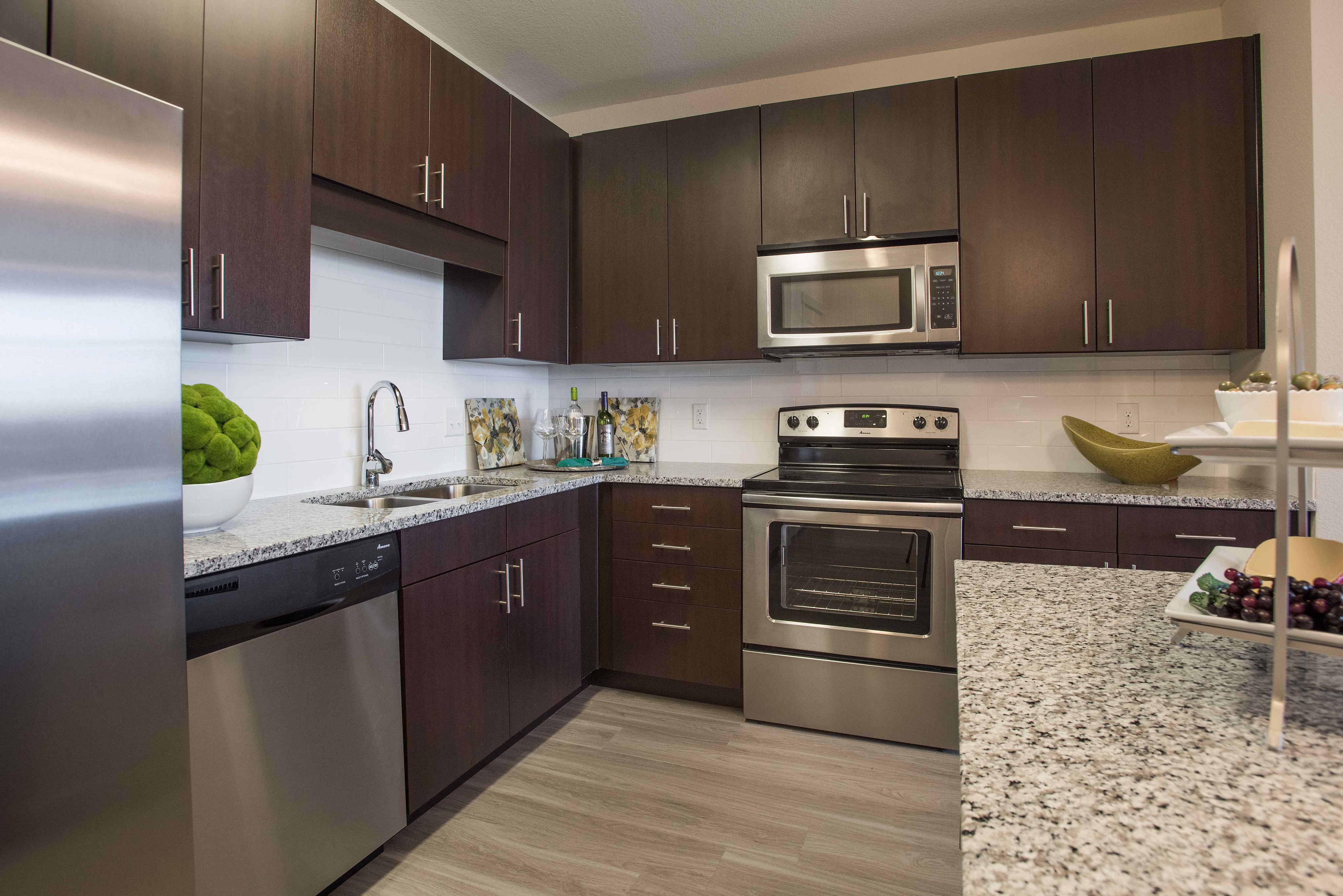 Modern kitchen showcasing sleek dark wood cabinets, stainless steel appliances, and elegant granite countertops.