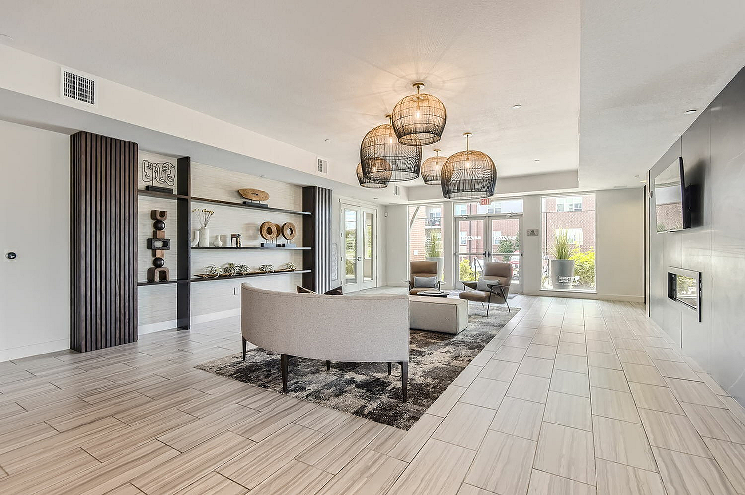 Elegant living room featuring modern decor, a stylish lounge area with plush seating, decorative shelving, and large windows filling the space with natural light.