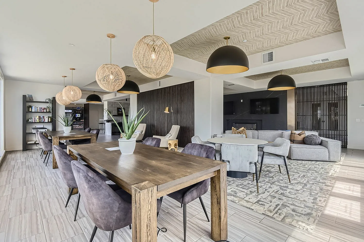 Chic modern apartment lounge with elegant wooden tables, plush seating, stylish pendant lighting, and a cozy entertainment area.