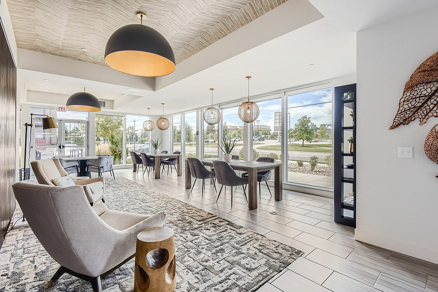 Modern lounge area with elegant armchairs, stylish wooden tables, and large windows offering scenic views, ideal for relaxation and social gatherings.