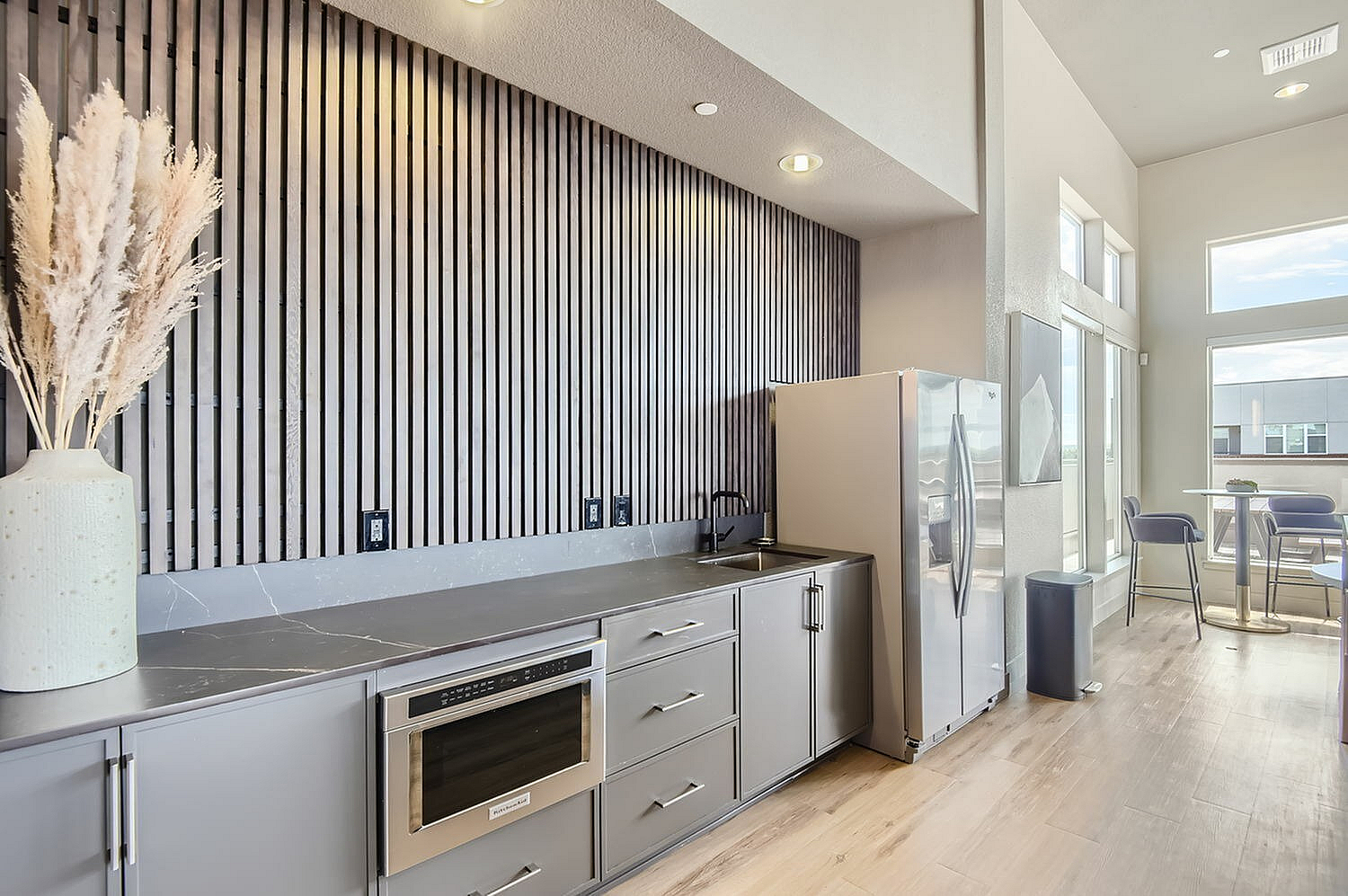 Modern kitchen with sleek cabinetry, stainless steel appliances, and a bright dining nook with large windows.