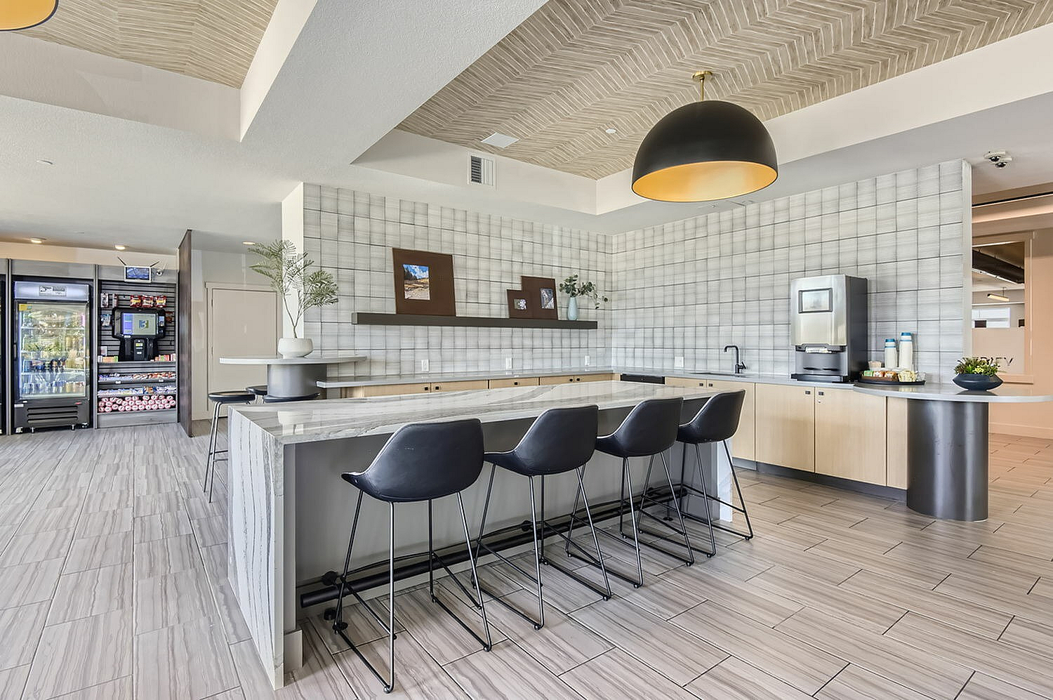 Modern communal kitchen space with elegant bar seating, sleek countertops, and a gourmet coffee station.