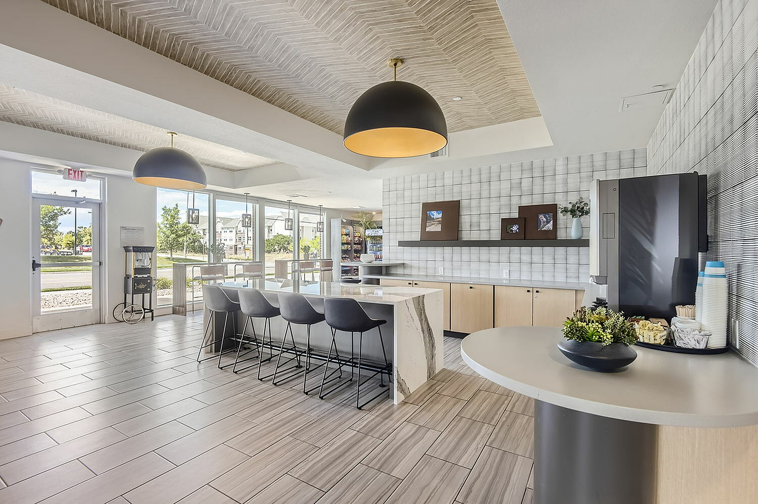 Bright and modern communal kitchen space with sleek countertops, bar seating, and natural light through large windows.