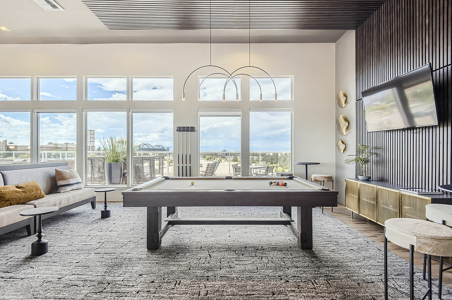 Spacious and elegant game room with a billiards table, modern seating, and large windows offering stunning views.