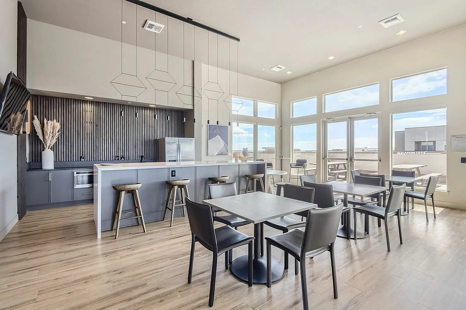 Modern communal kitchen and dining area with ample natural light, sleek countertops, and stylish seating.